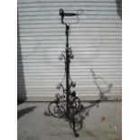 A wrought iron extendable torchiere with floral design to the base.