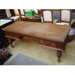 A teak 20th Century Indonesian desk, on turned legs with two drawers.