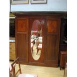 An Edwardian mahogany 3 door wardrobe with two internal drawers, shelving, a clothing rack, coat
