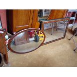 A reproduction framed wall mirror along with a wooden framed oval wall mirror, both with bevelled