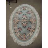 A modern oval Chinese rug, with floral design on a greeen ground.