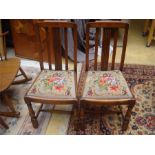 A pair of mahogany dining chairs with drop in embroidered seats.