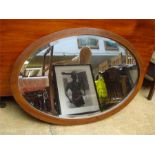 A wooden framed oval wall mirror with bevelled gla