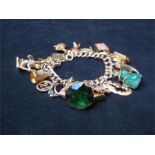 A 9ct gold double curb link charm bracelet, marked 375, with approx twenty six assorted charms, many