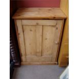 A rustic pine cupboard, the single door opening to