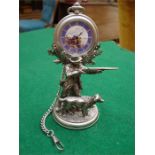 A plated pocket watch stand with a gamekeeper and gun dog, with pocket watch including chain.