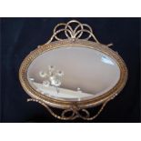 A giltwood oval wall mirros, with ribbon cresting