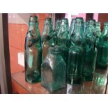 Seven green Cod bottles with marbles together with one other.