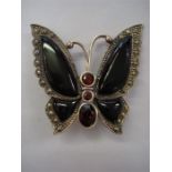 An Art Deco style silver (marked 925) onyx and garnet set brooch, in the form of a butterfly with