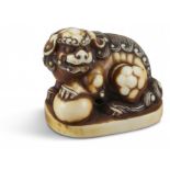 NETSUKE: SHISHI. Japan. Edo-Zeit. 2. H. 19. Jh. Shishi, sitzend auf gerundetem rechteckigem