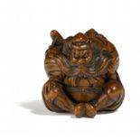 NETSUKE: SITZENDER SHÔKI. Japan. Edo-Zeit. 19. Jh. Buchsbaum mit dunkel eingefärbten Details.