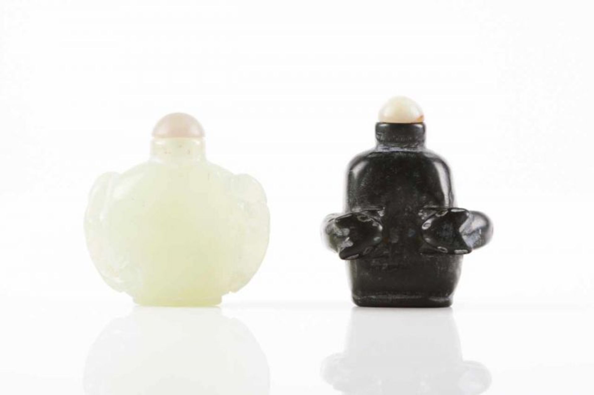 Two snuff-bottles Jade and black marble Carved decoration China (adapted covers) Height: 6 cm