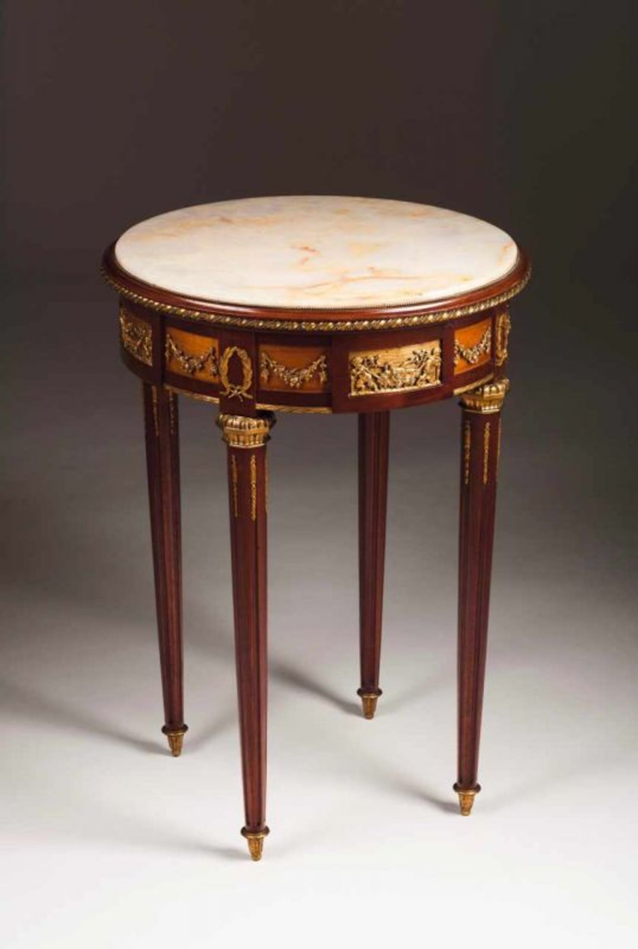 A Louis XVI style occasional table Mahogany and other woods Gilt bronze mounts with putti, garlands
