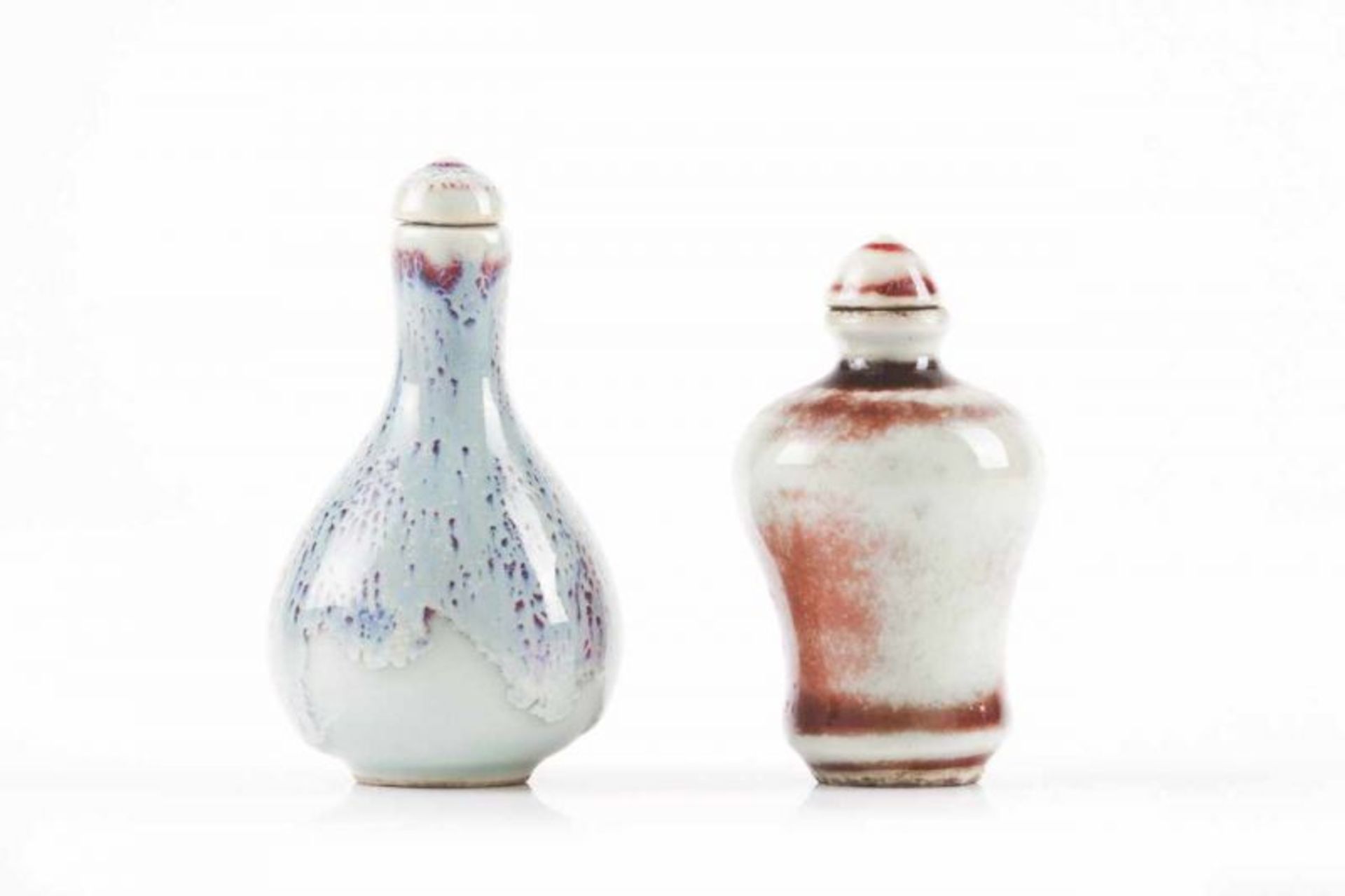 Two snuff-bottles Chinese porcelain Flambé glazing Marked at the base Height: 8,5 cm Height: 7,5 cm