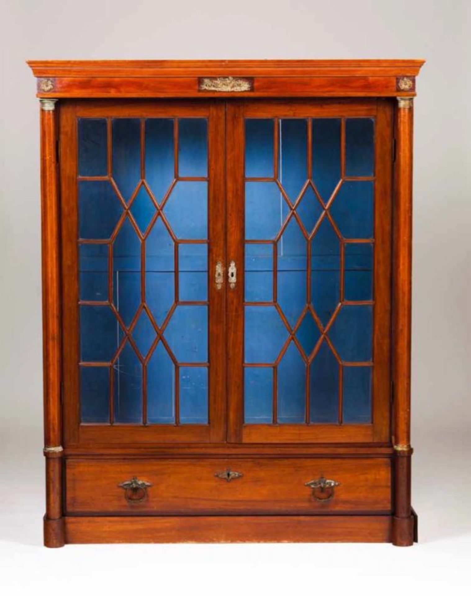An Empire style bookcase Mahogany with gilt metal mounts Glazed doors and one long drawer