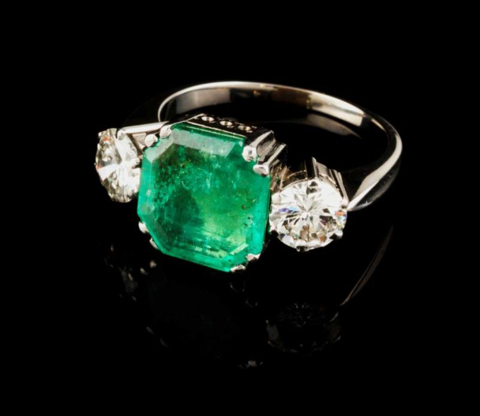 A ring Set in white gold with one emerald cut emerald and two brilliant cut diamonds (ca. 1,35ct)