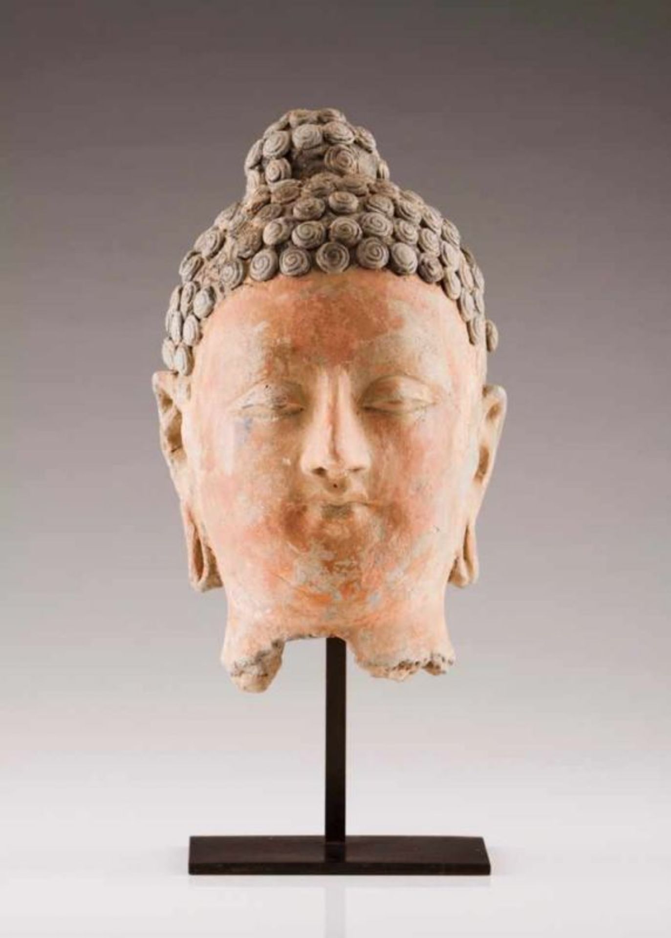 A Buddha's head Terracotta with traces of polyhromy Sculpture with serene face, arched eyebrows,