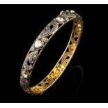 A bangle 9kt gold and silver set with single cut diamonds and foiled irregualr cut diamonds