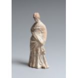 Fine statuette tanagréenne féminine à la coiffe au chignon, une main sur les [...]