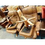 Two brown leather swivel arm chairs with matching foot rests