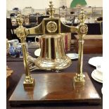 Heavy brass bell on ornate brass frame standing on mahogany base,