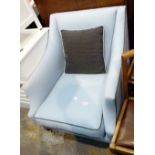 Pale blue fabric covered fireside chair with castor feet to front