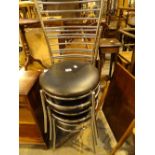 Three chrome ladder back dining chairs with black upholstered seats