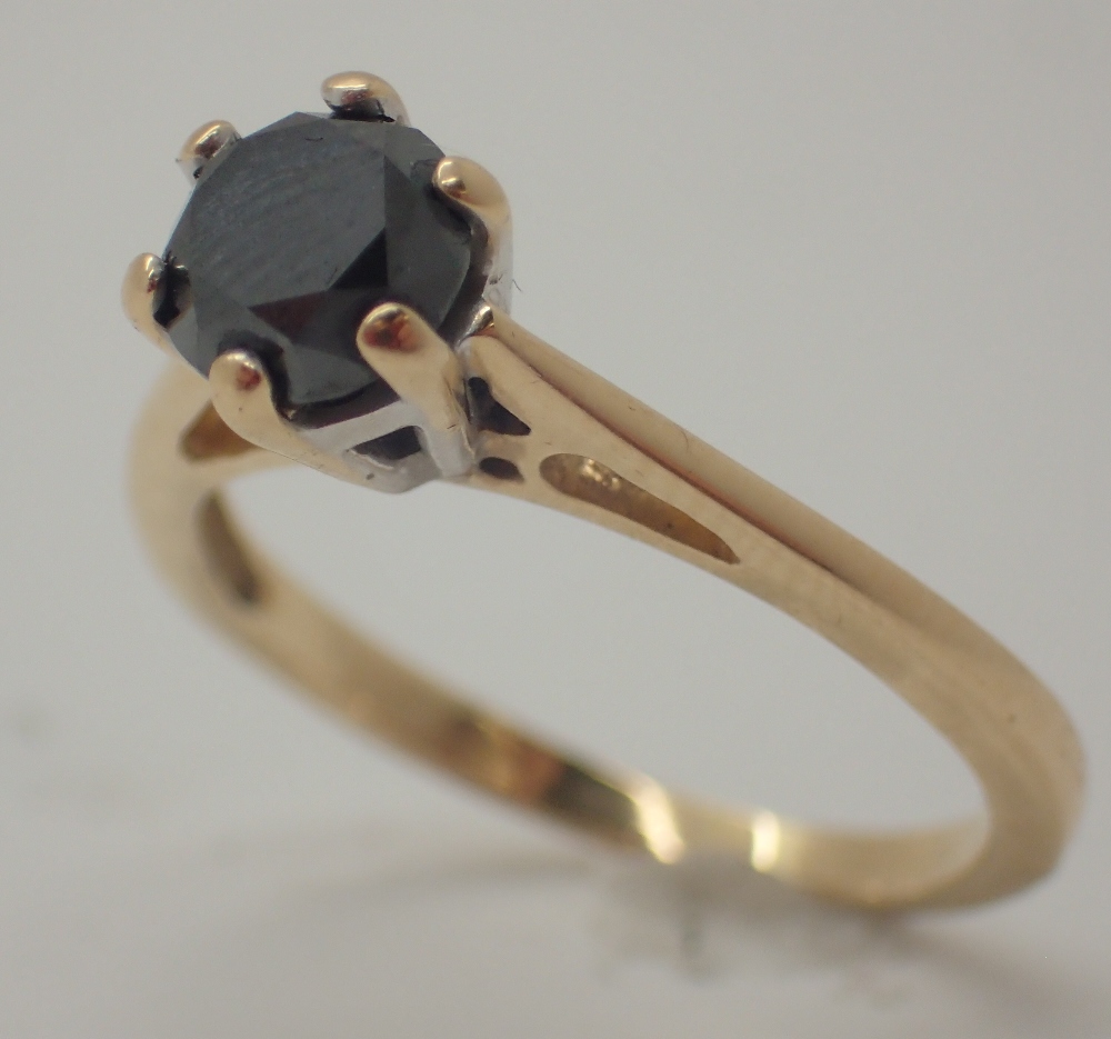 Black diamond solitaire ring in a white gold setting on a yellow gold shank size N approximately 0.