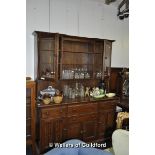 Oak dresser with twin glazed cupboard and open shelves above a four-drawer four-door sideboard base,