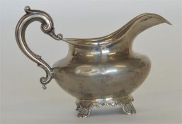 A heavy silver helmet shaped cream jug with scroll