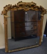 A large gilt over mantle mirror decorated with scr
