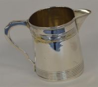 A Georgian tapering cream jug with reeded body and