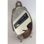 An oval picture frame, the top embossed with scrol