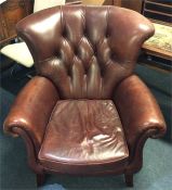 A large button back leather armchair on splayed su