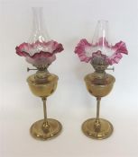 A pair of small brass lamps with cranberry shades.