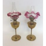 A pair of small brass lamps with cranberry shades.