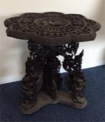 A small carved Eastern table on three scroll suppo
