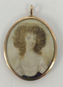 An oval gold framed miniature of a lady with hair