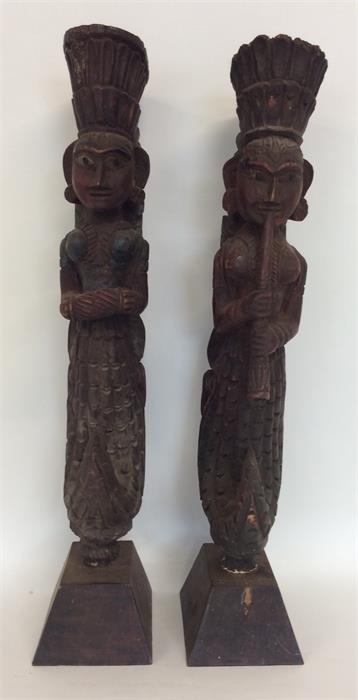 A pair of tall carved painted door stops of South