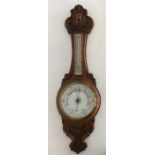 An oak carved barometer with scroll decoration. Es