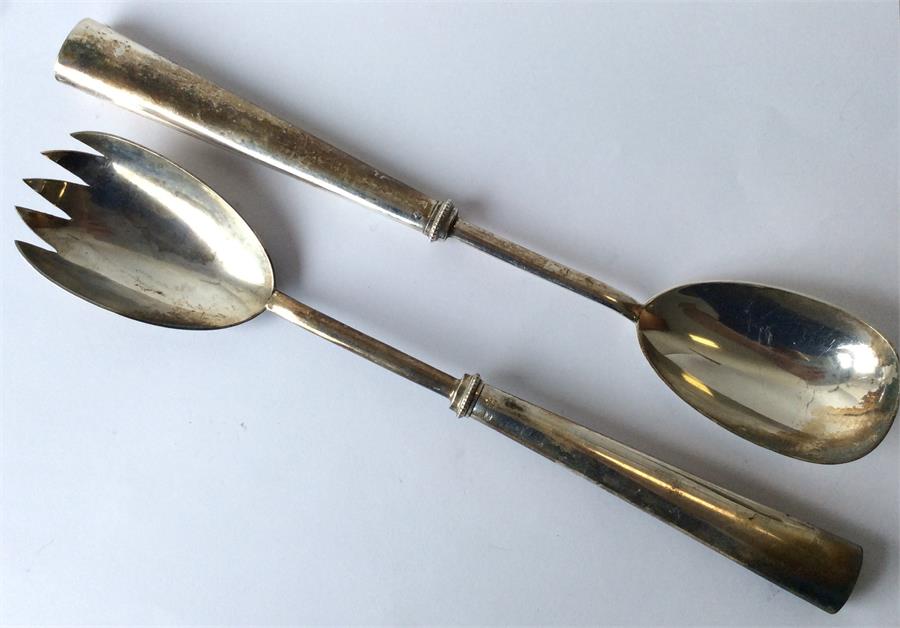 A large pair of salad servers with tapering handle