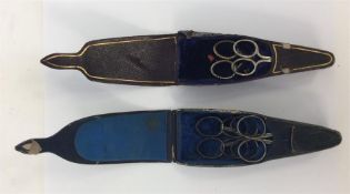 Two boxed pairs of travelling scissors within a le