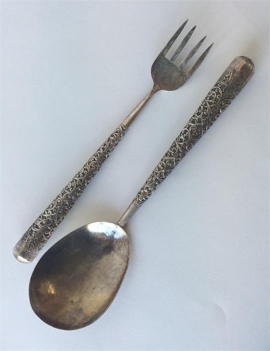 A pair of Indian salad servers with floral decorat