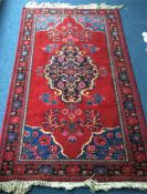 A large red ground rug with blue medallion. Approx