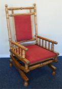 A large pine rocking chair with red upholstered de