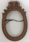 A small oval carved oak picture frame with ribbon