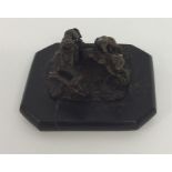 A small bronzed statue of a hunting scene on rocky