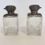 A pair of square silver top scent bottles with hin