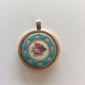 An enamelled circular pendant decorated with flowe