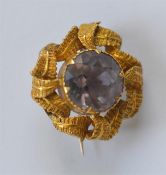 A small gold amethyst circular brooch attractively